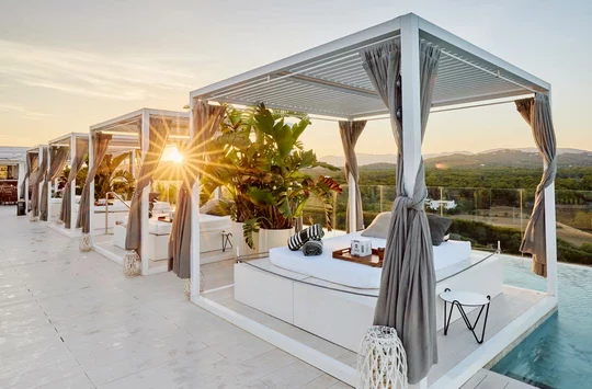 Ein Pool mit Liegestühlen und Sonnenschirmen bei Sonnenuntergang.